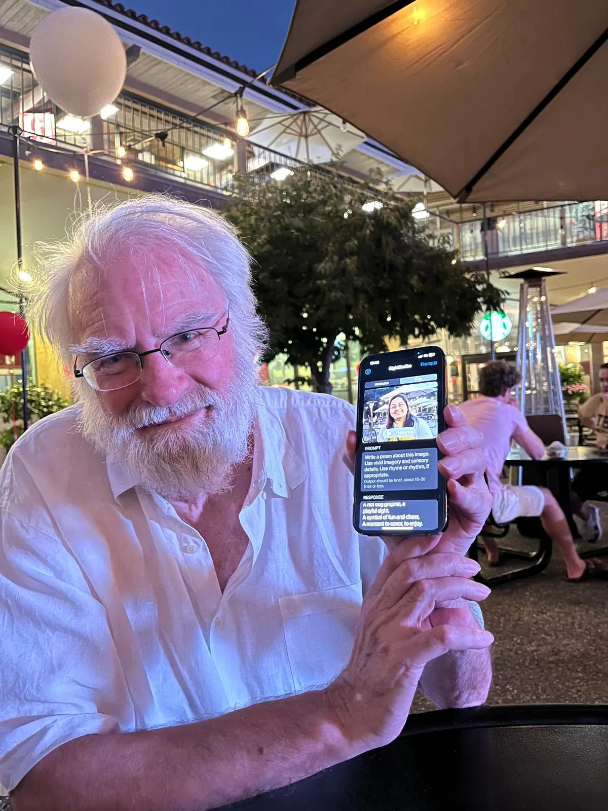 An 80-year-old man at a Stanford AI meetup showing his SightScribe app with a poem on screen